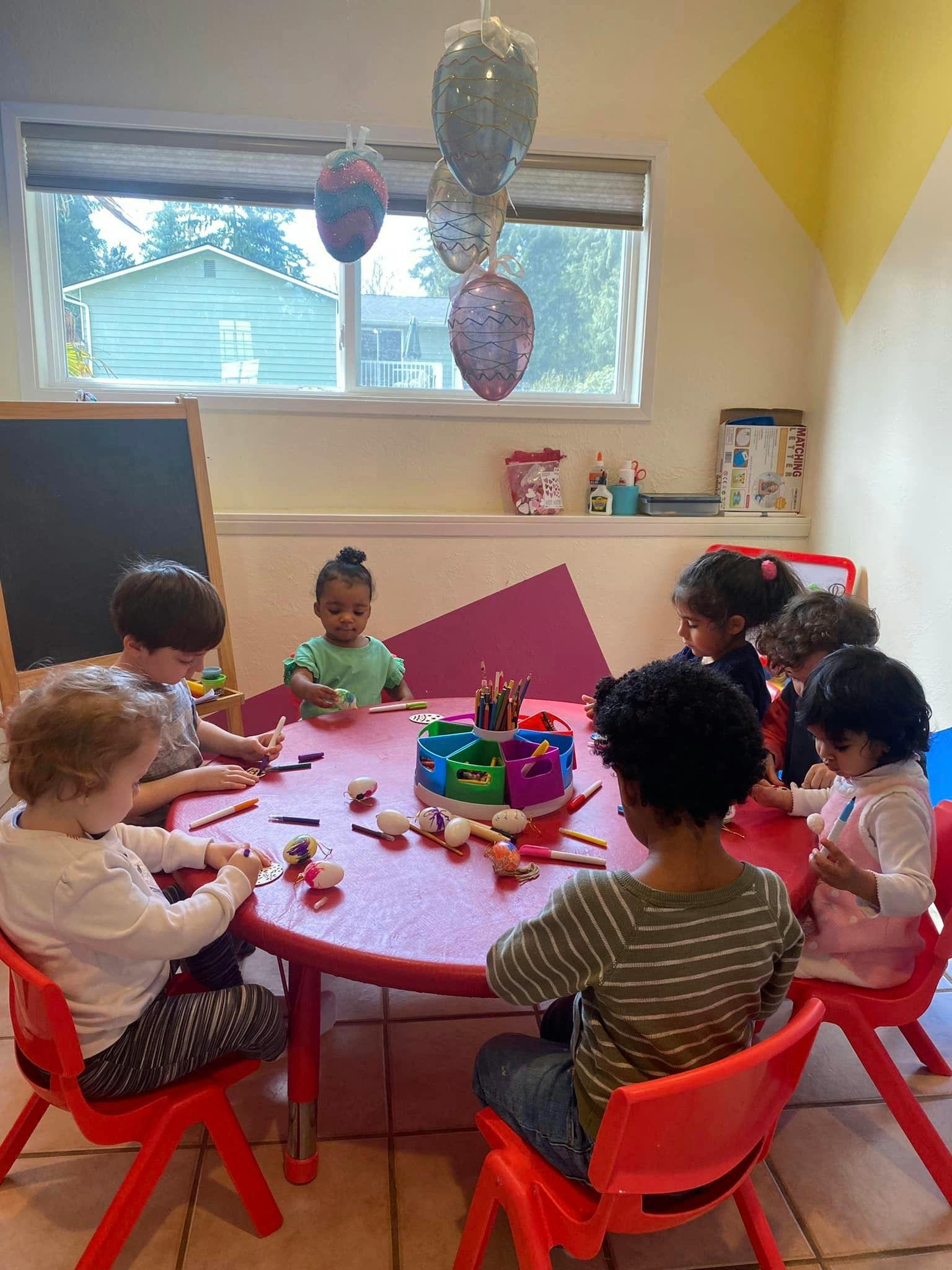Children sitting around a table with art supplies in a classroom