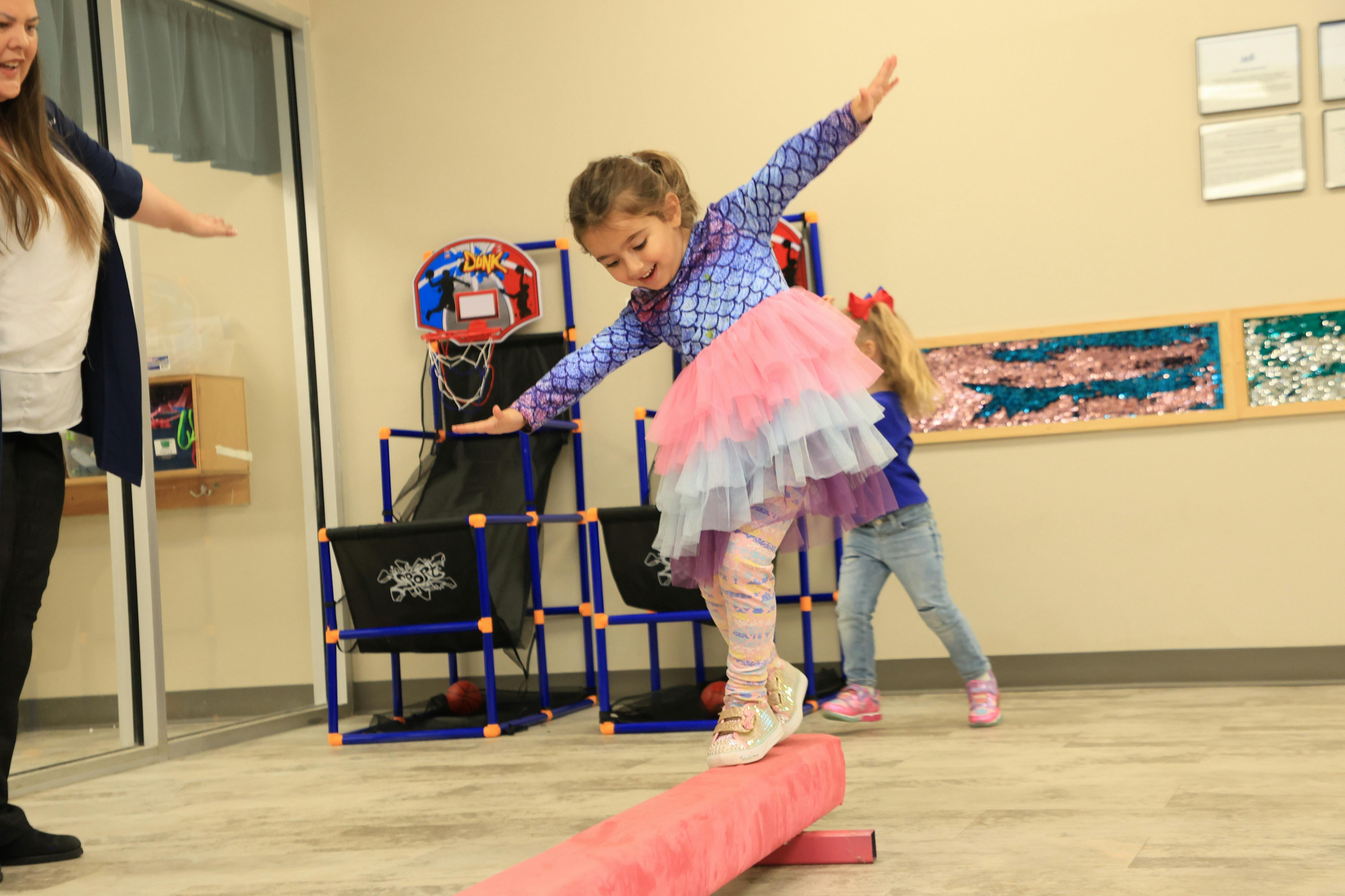 Child balancing on a pink beam with arms outstretched