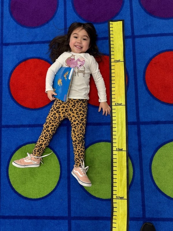 Child lying on a carpet next to a height measurement chart