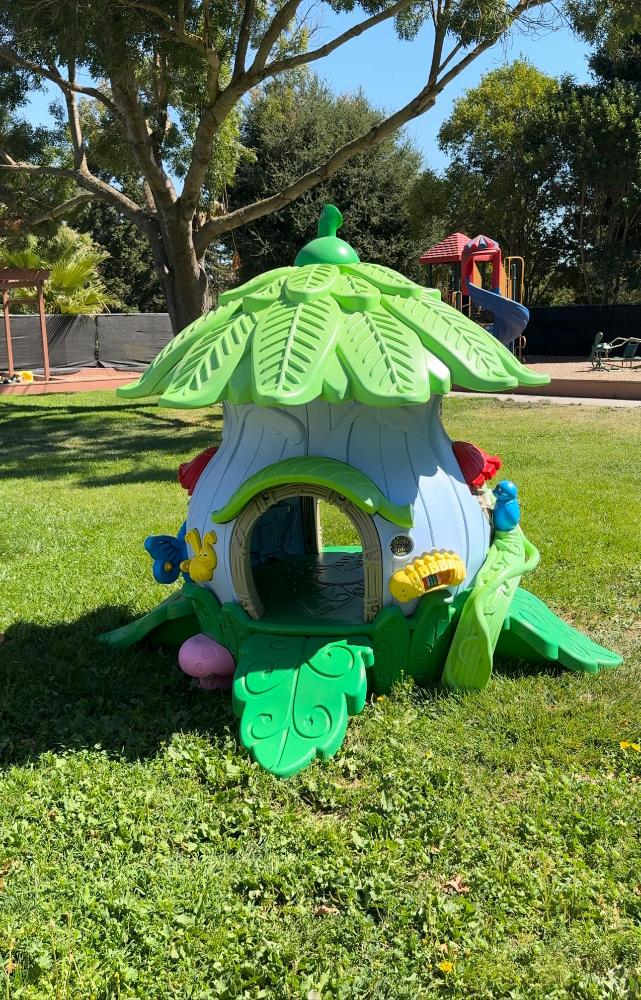 Playhouse shaped like a tree stump with a green leaf roof