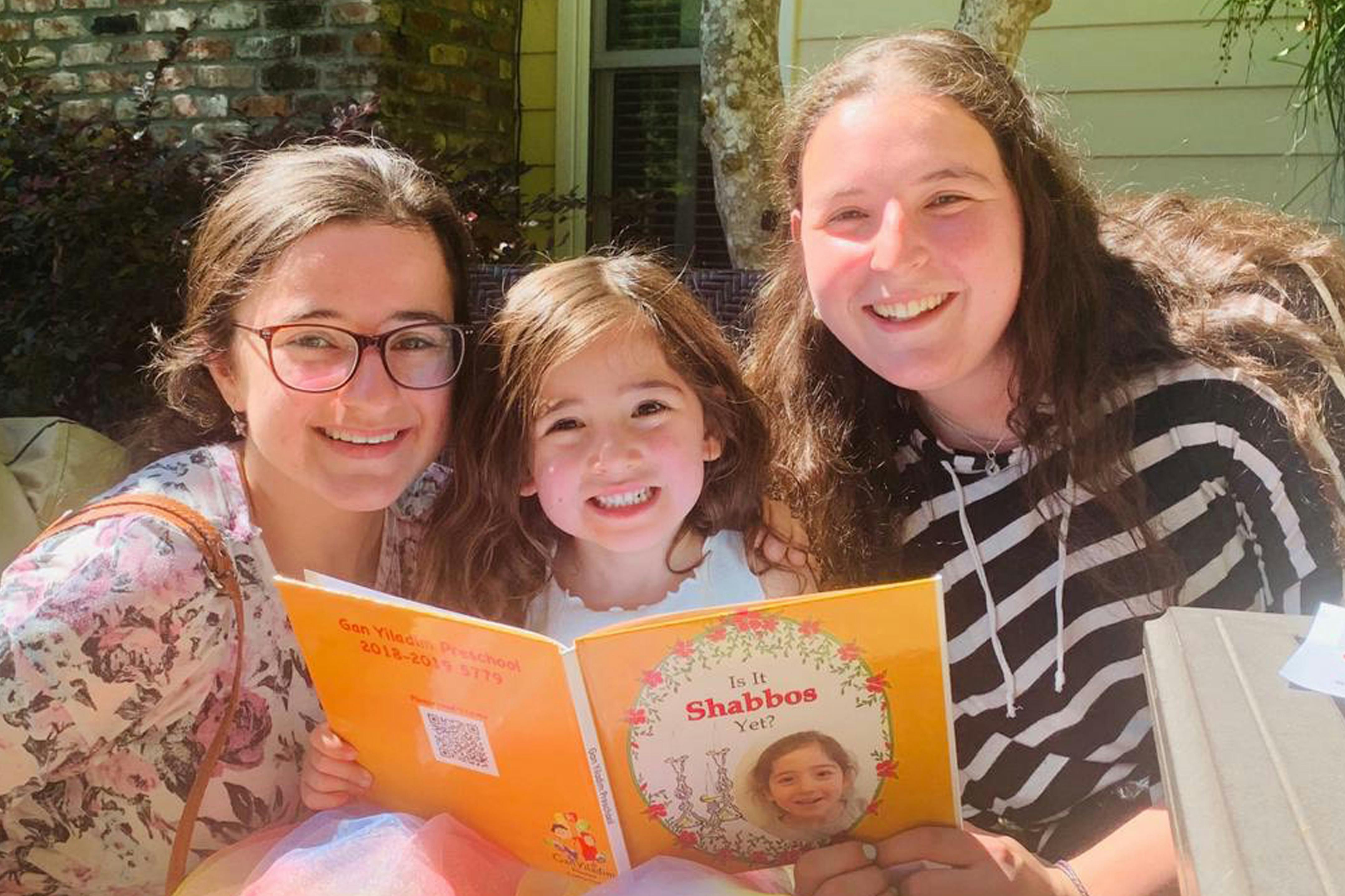 Two people and a child looking at an open book