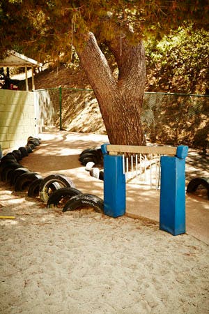 Outdoor play area with sand, tires, and a tree