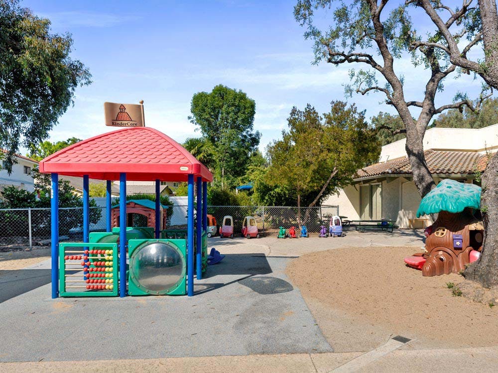 Outdoor playground with a red-roofed structure and other play equipment