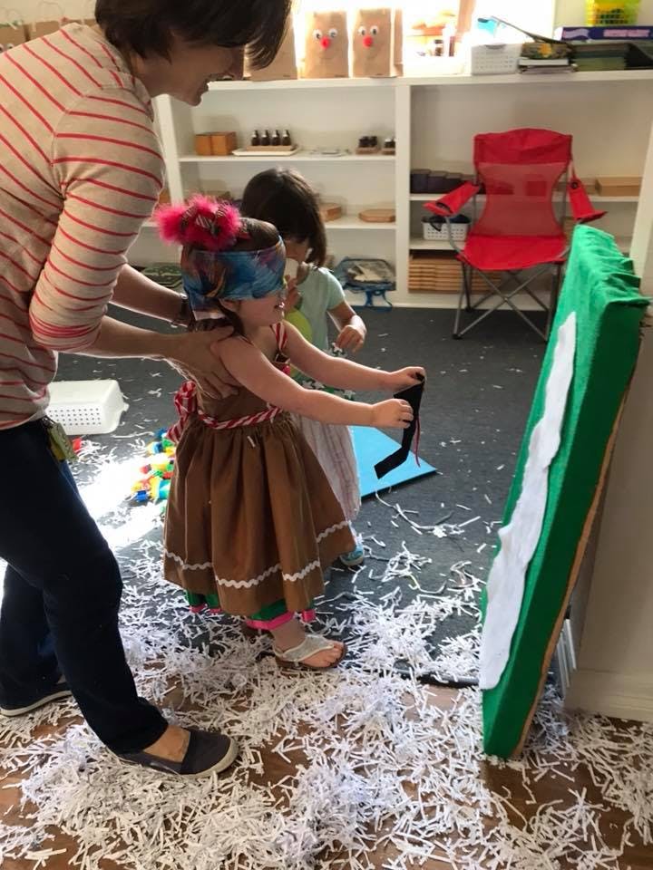 Person helping a child with a blindfold play a game