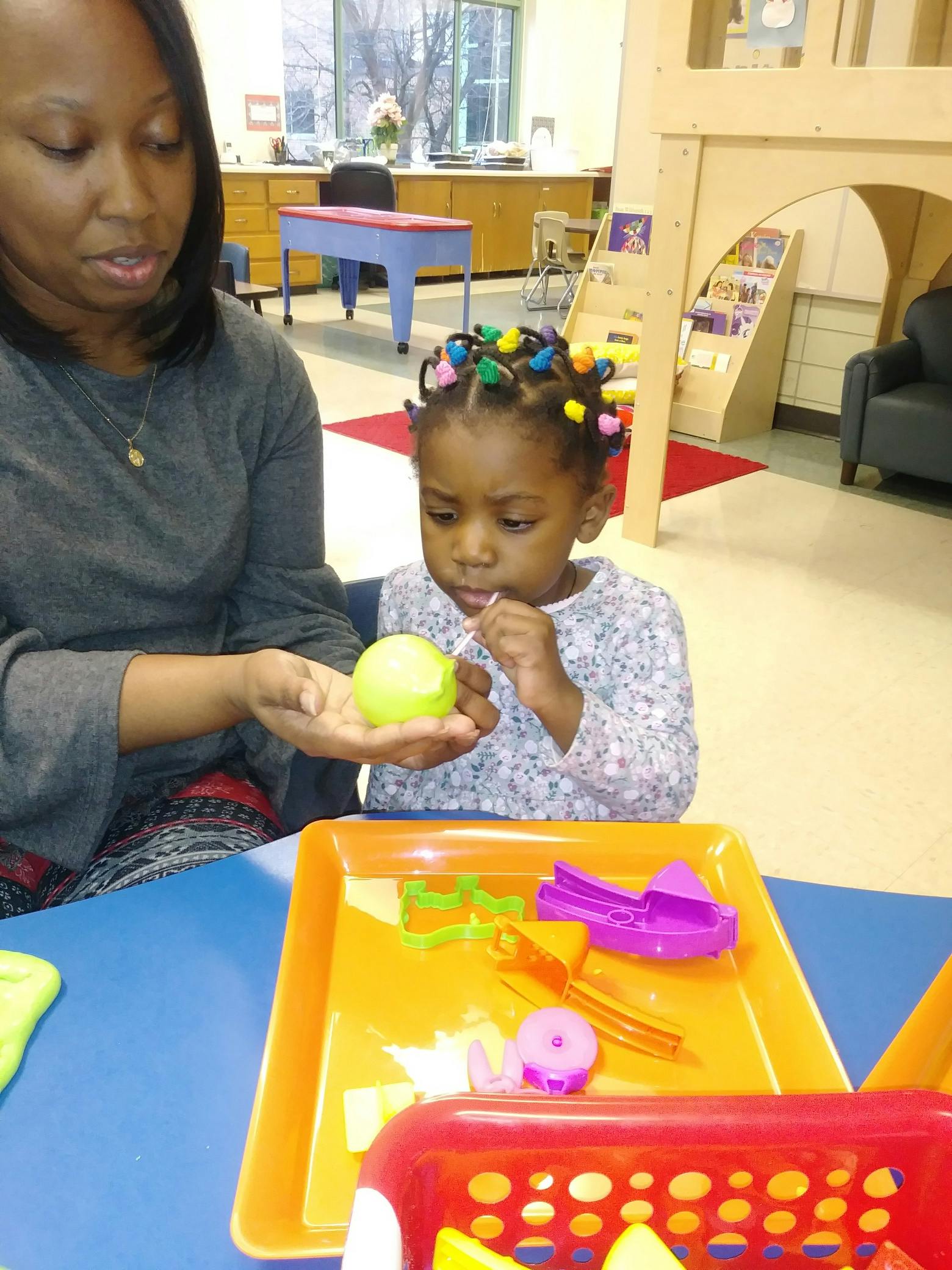 Adult holding a yellow ball for a child