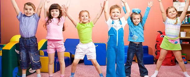 Six children with arms raised in a classroom