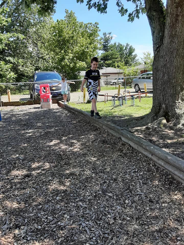 Child walking on a wooden beam on a playground