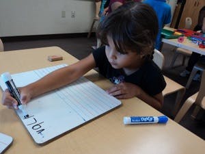 Child writing on a whiteboard at a table