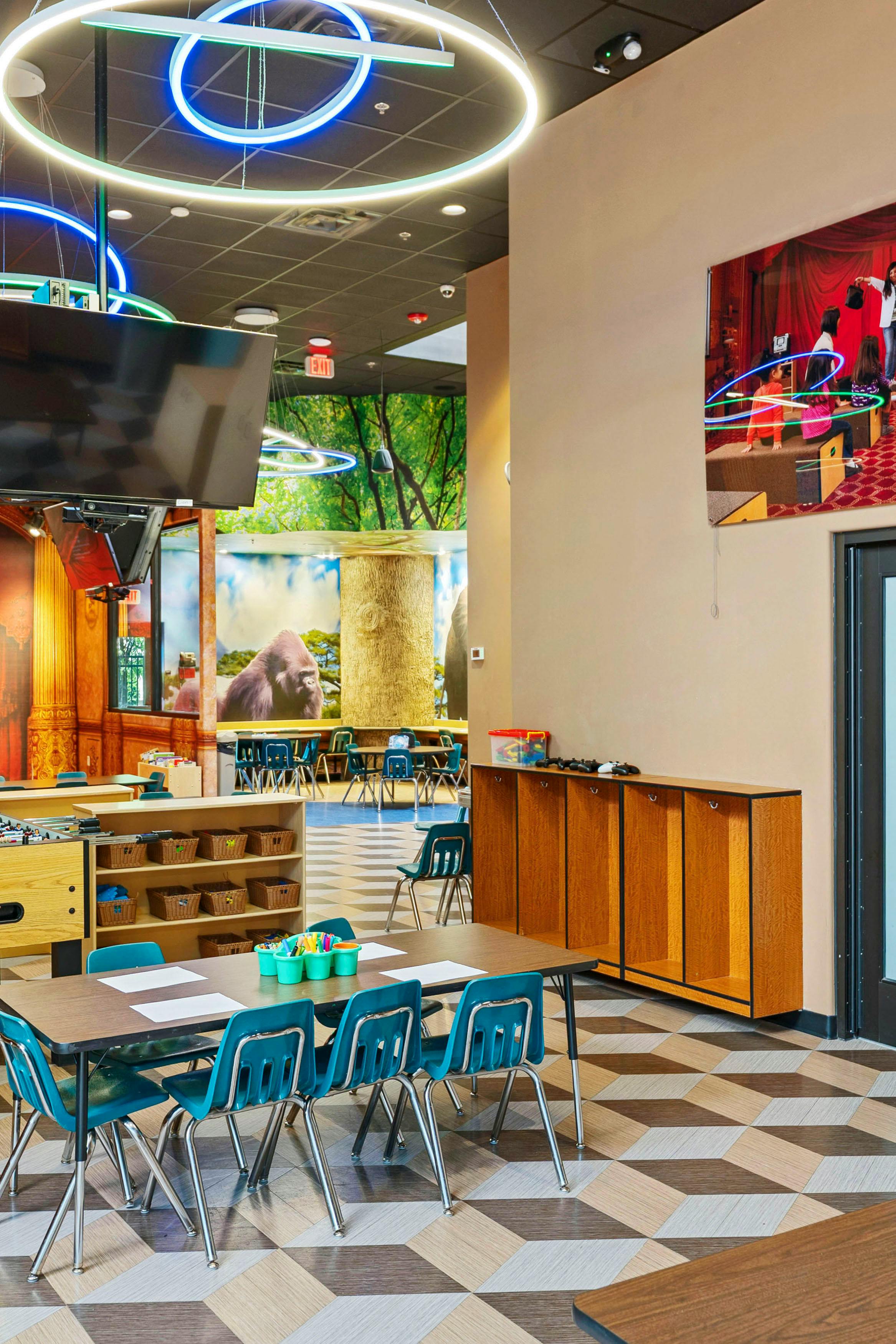 Children's activity room with tables, chairs, and colorful murals