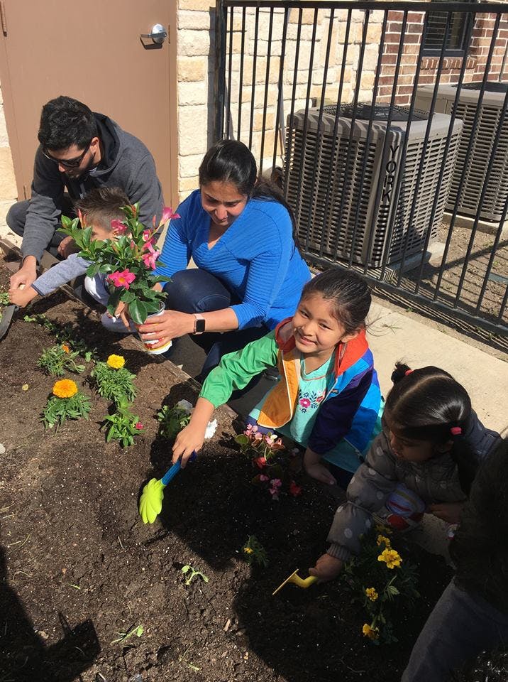 Adults and children planting flowers in soil