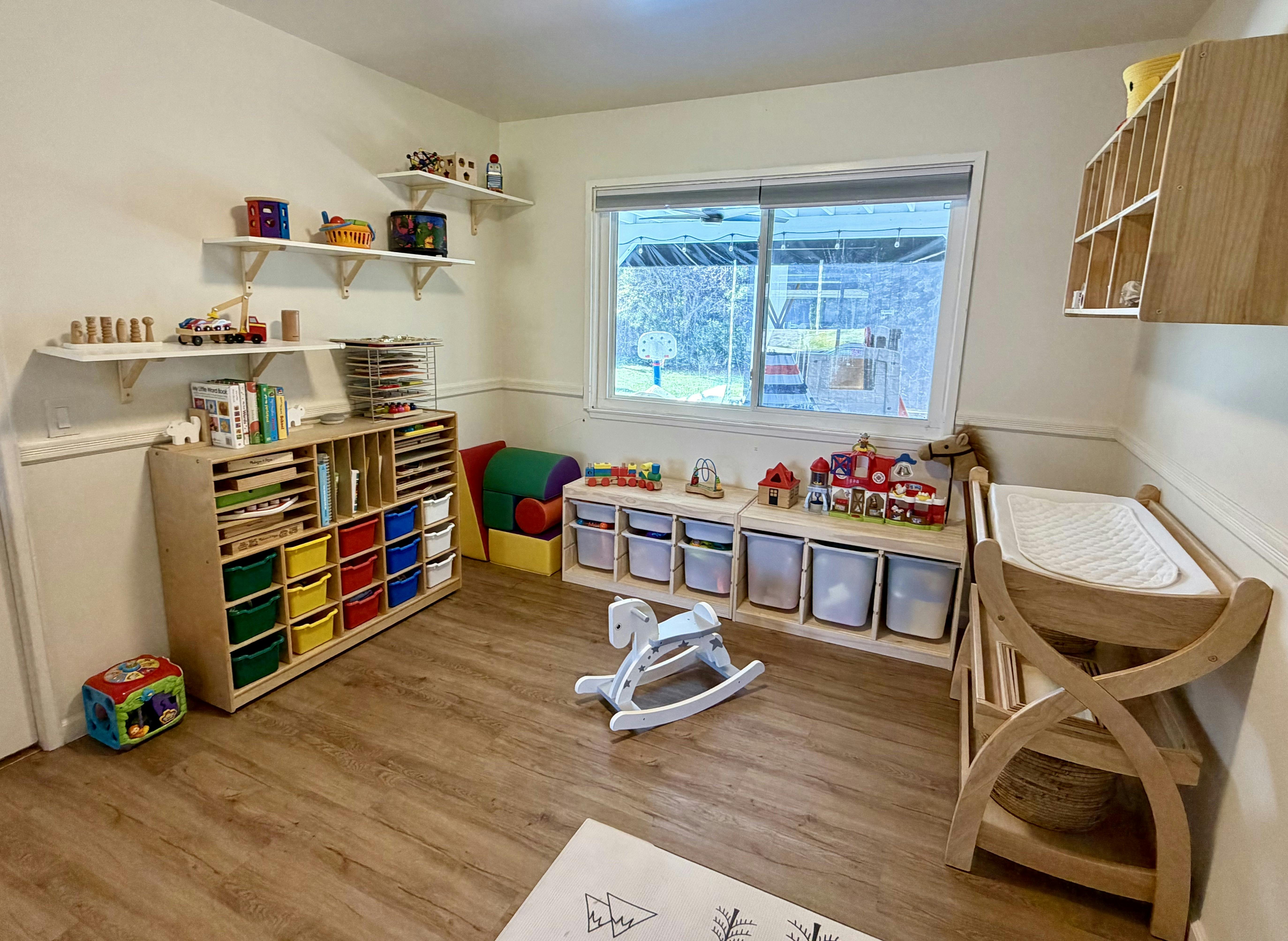 Children's playroom with shelves full of toys and a rocking horse on the floor