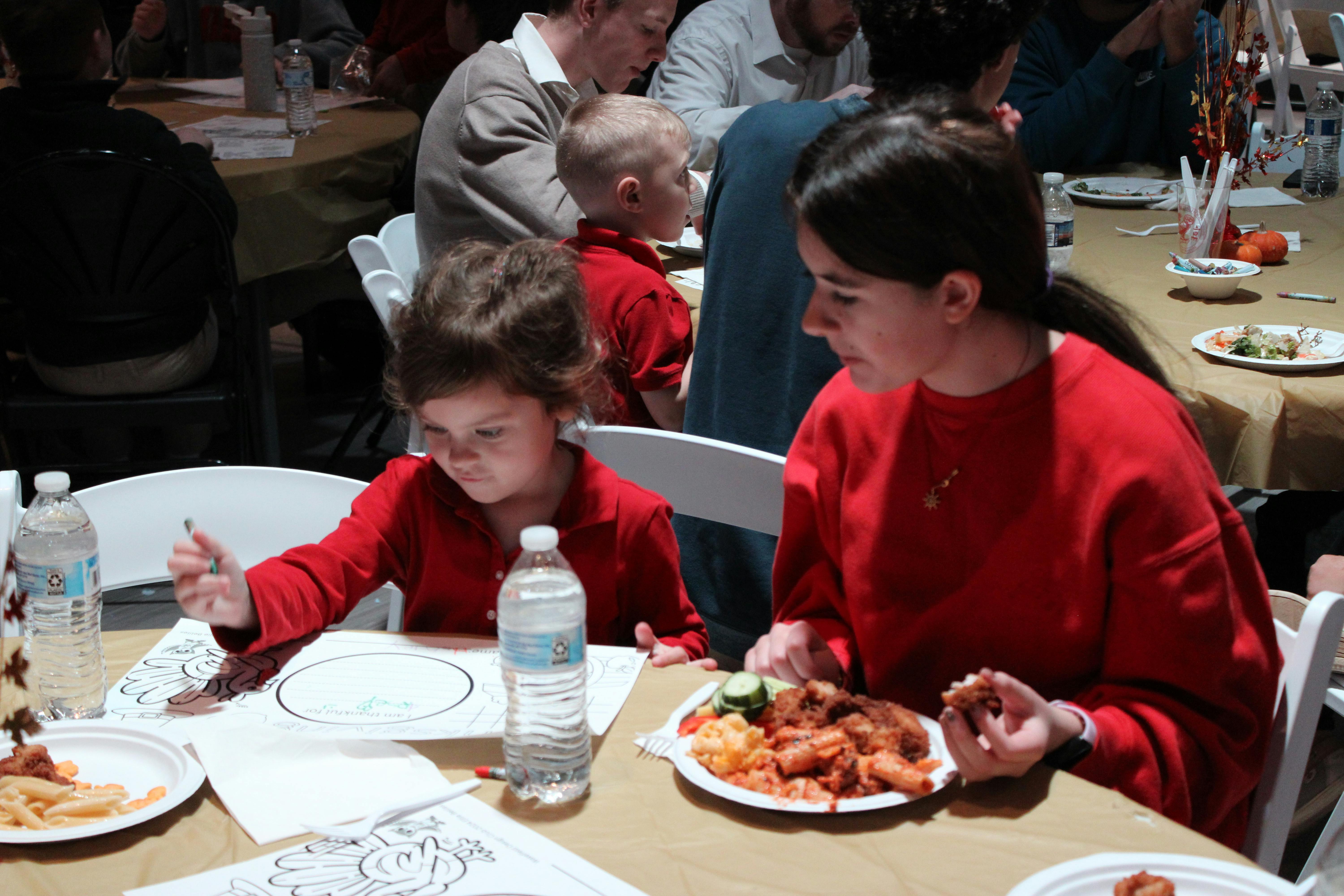 Person and child in red shirts at a table with food and drinks