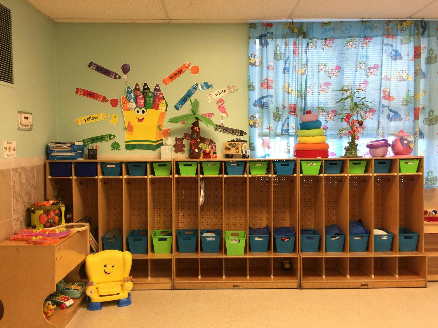 Classroom with cubbies, colorful bins, and crayon decorations on the wall