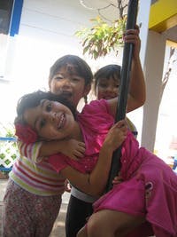 Three children playing on a pole