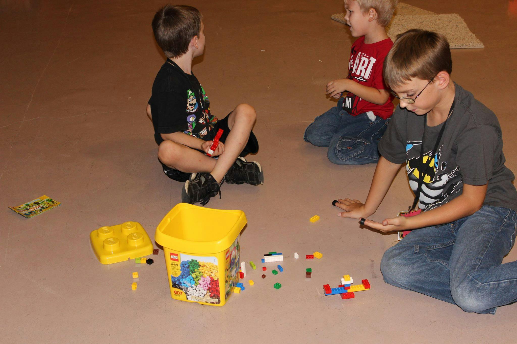 Three children playing with building blocks on the floor