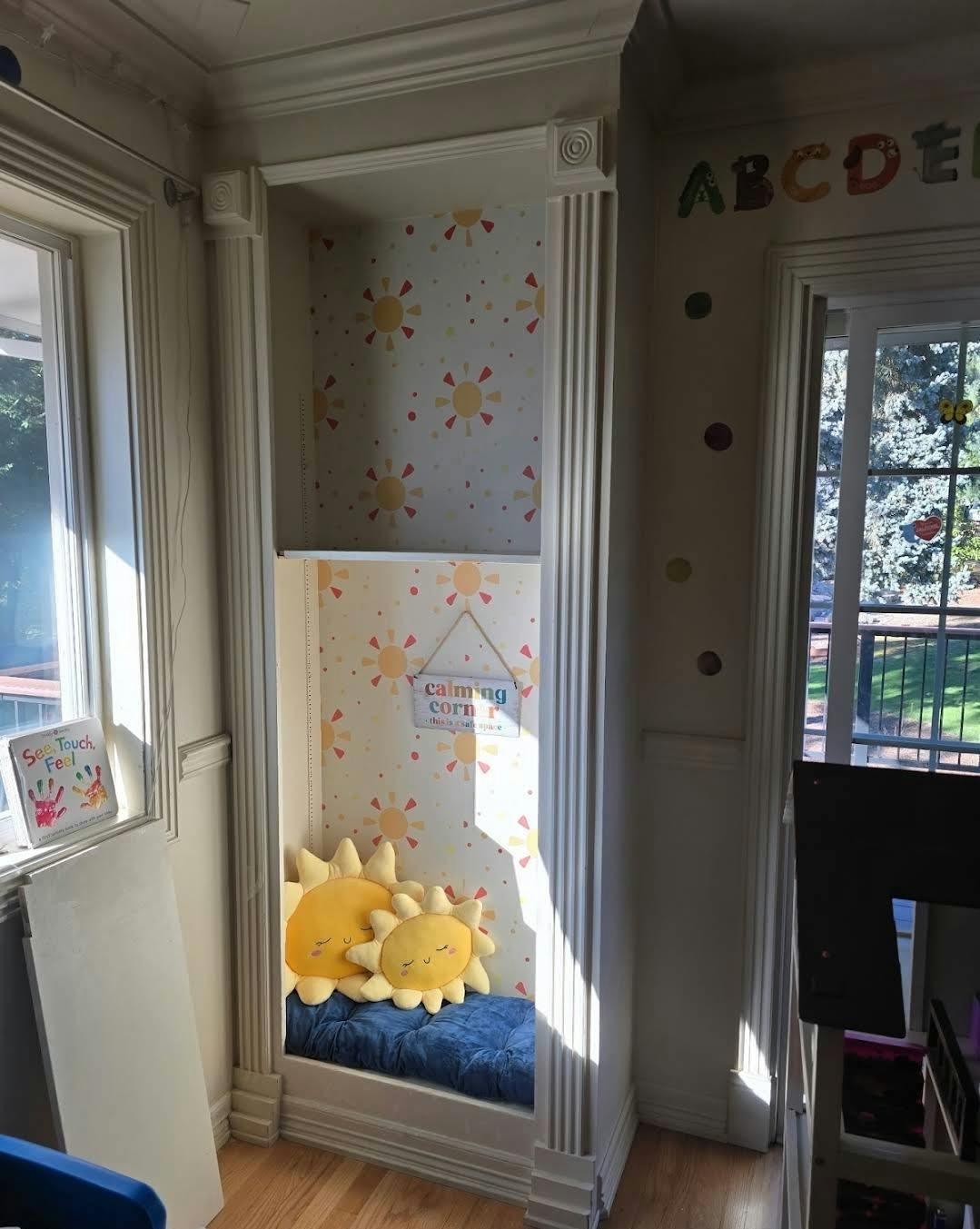 A built-in reading nook with sun-patterned wallpaper and sun pillows
