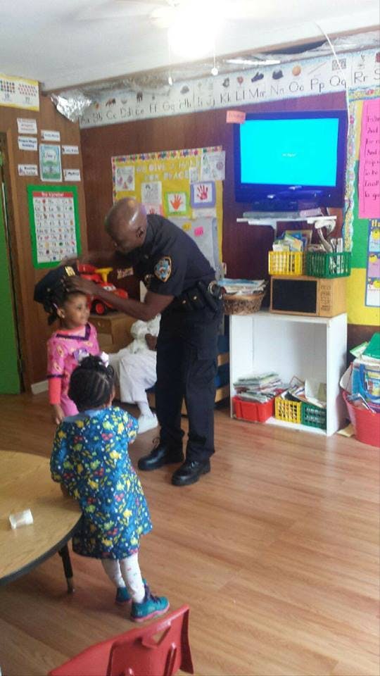 Person in uniform interacting with two children in a classroom