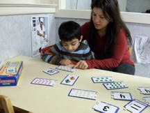 Adult and child at table with number cards