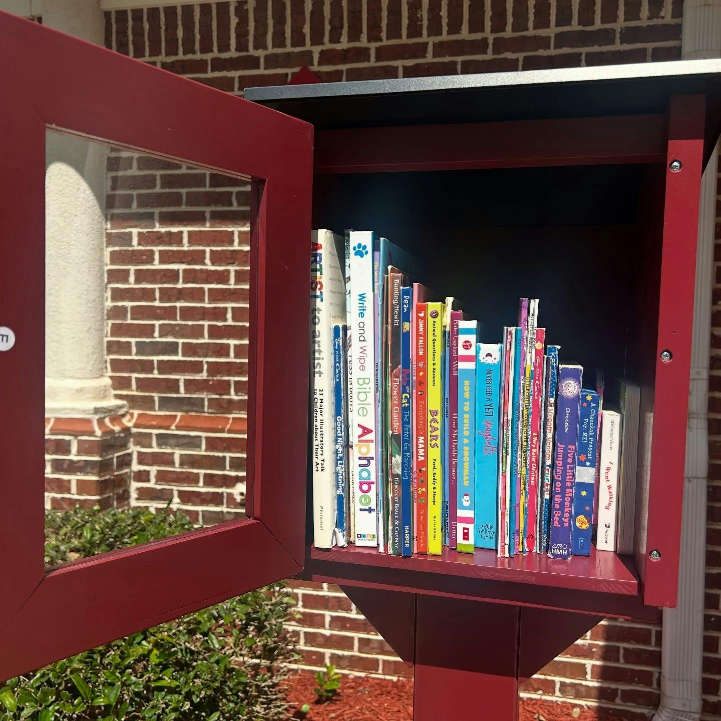 Open red little free library box filled with books