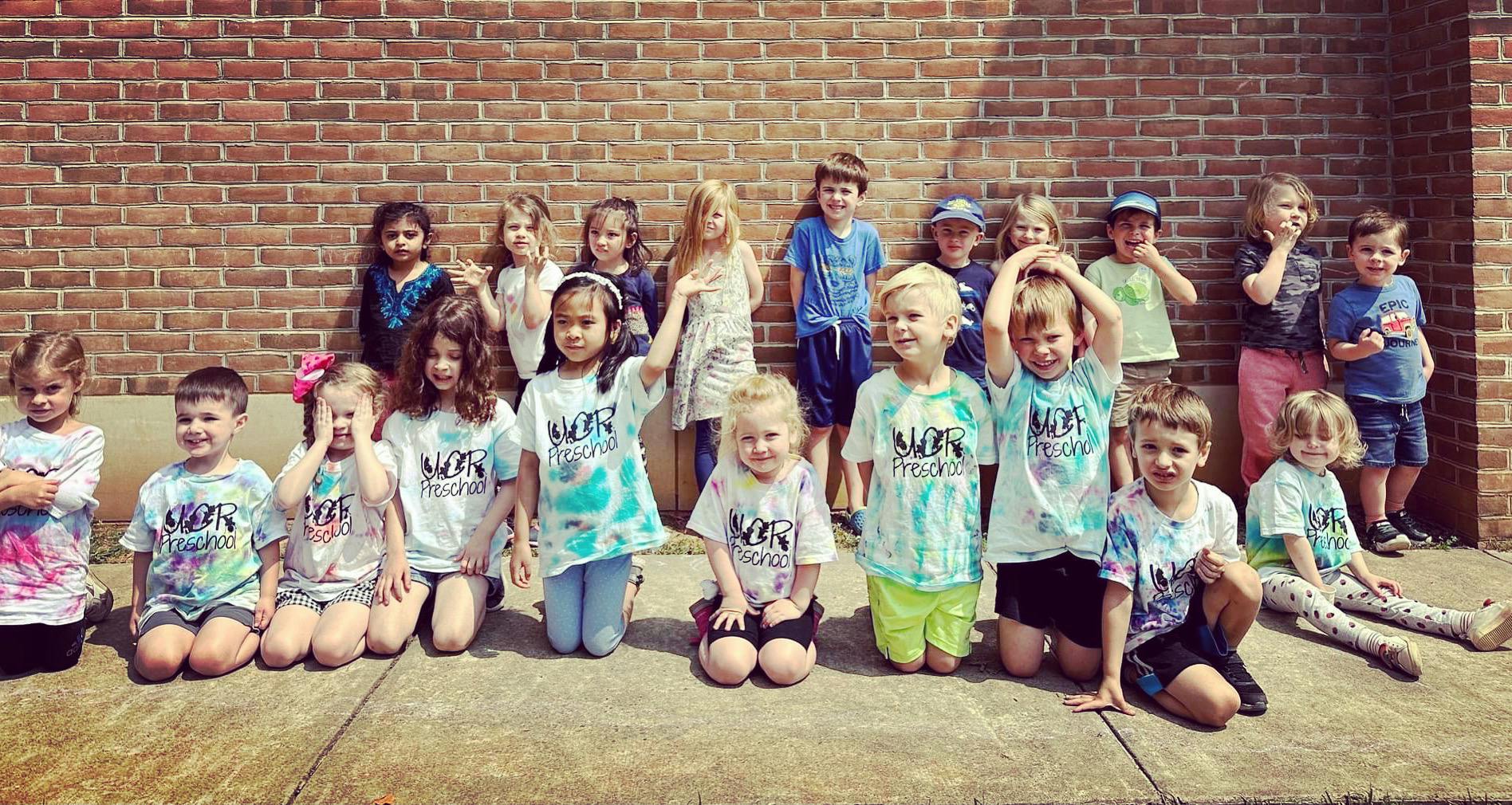 Group of children wearing "WOR Preschool" shirts, some kneeling, some standing