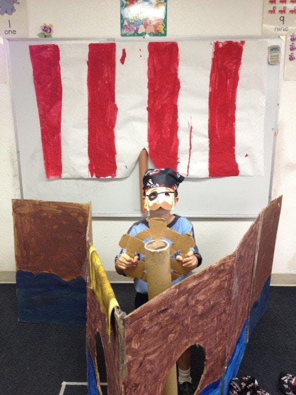 Child in pirate costume in a cardboard boat