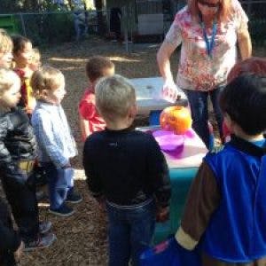Adult and children gathered around a table with a pumpkin
