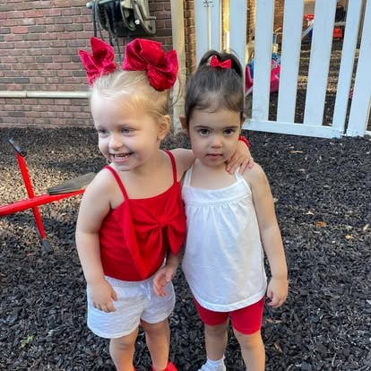 Two children standing together, one with arm around the other