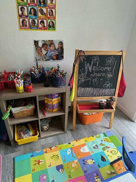 Classroom corner with art supplies, a drum, and a chalkboard sign