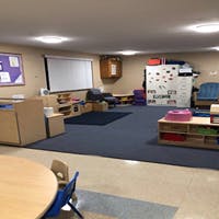 Empty classroom with tables, chairs, and play areas