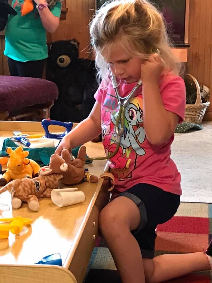 Child playing with a stethoscope and stuffed animals