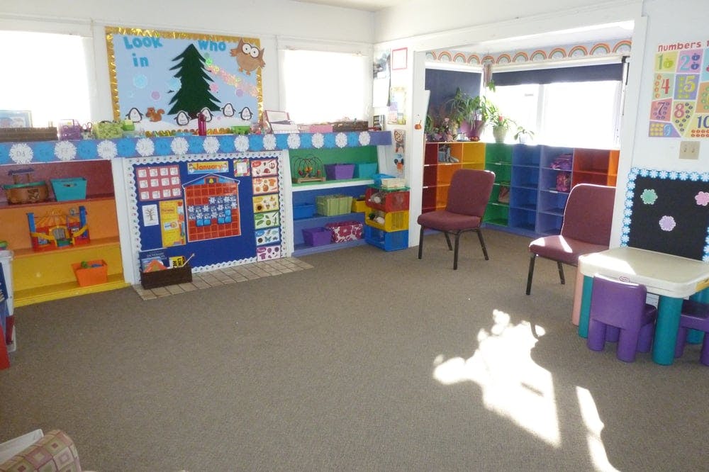 Classroom with colorful shelves, chairs, and a bulletin board