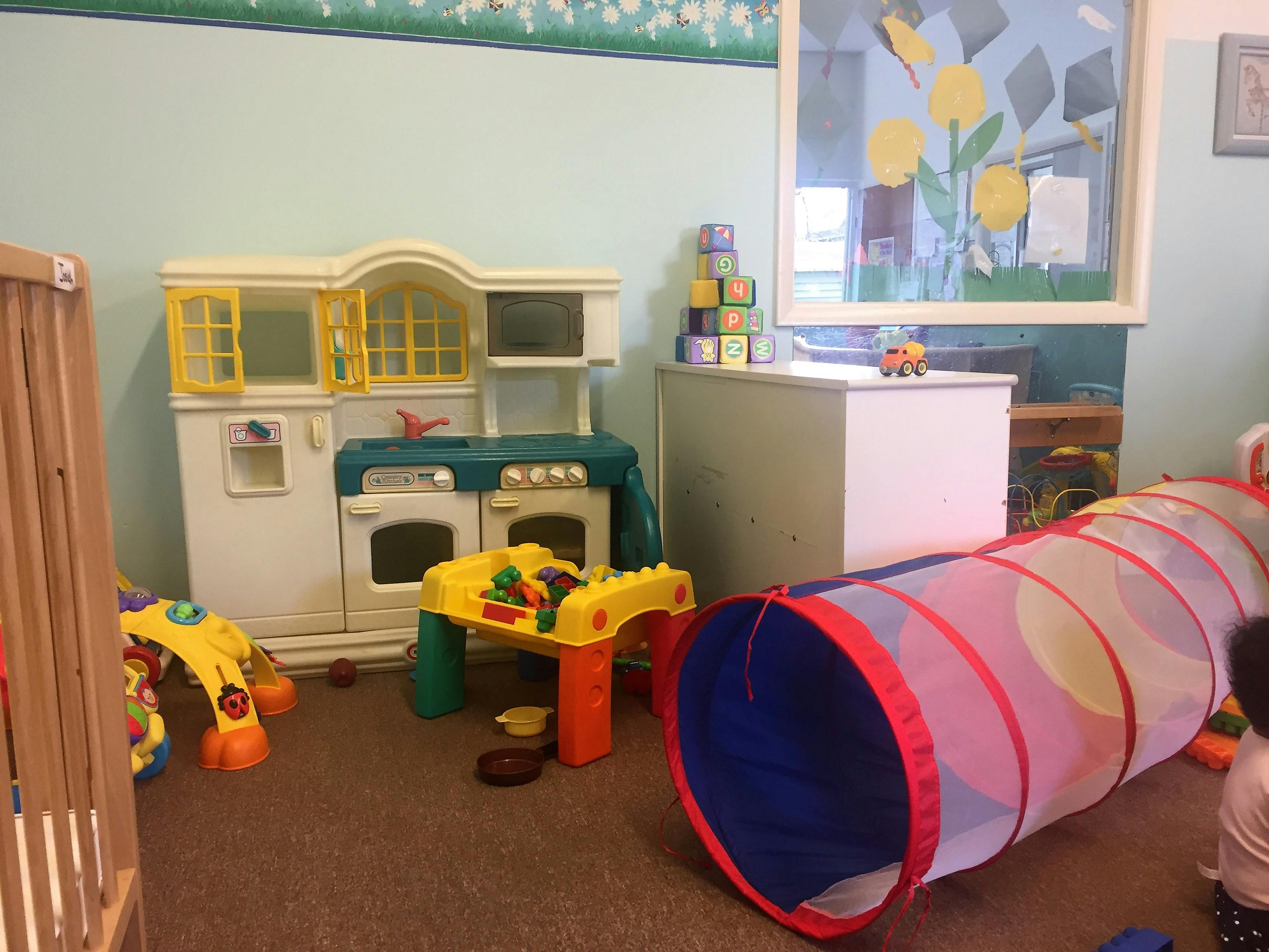 Play kitchen, activity table, and play tunnel in a room