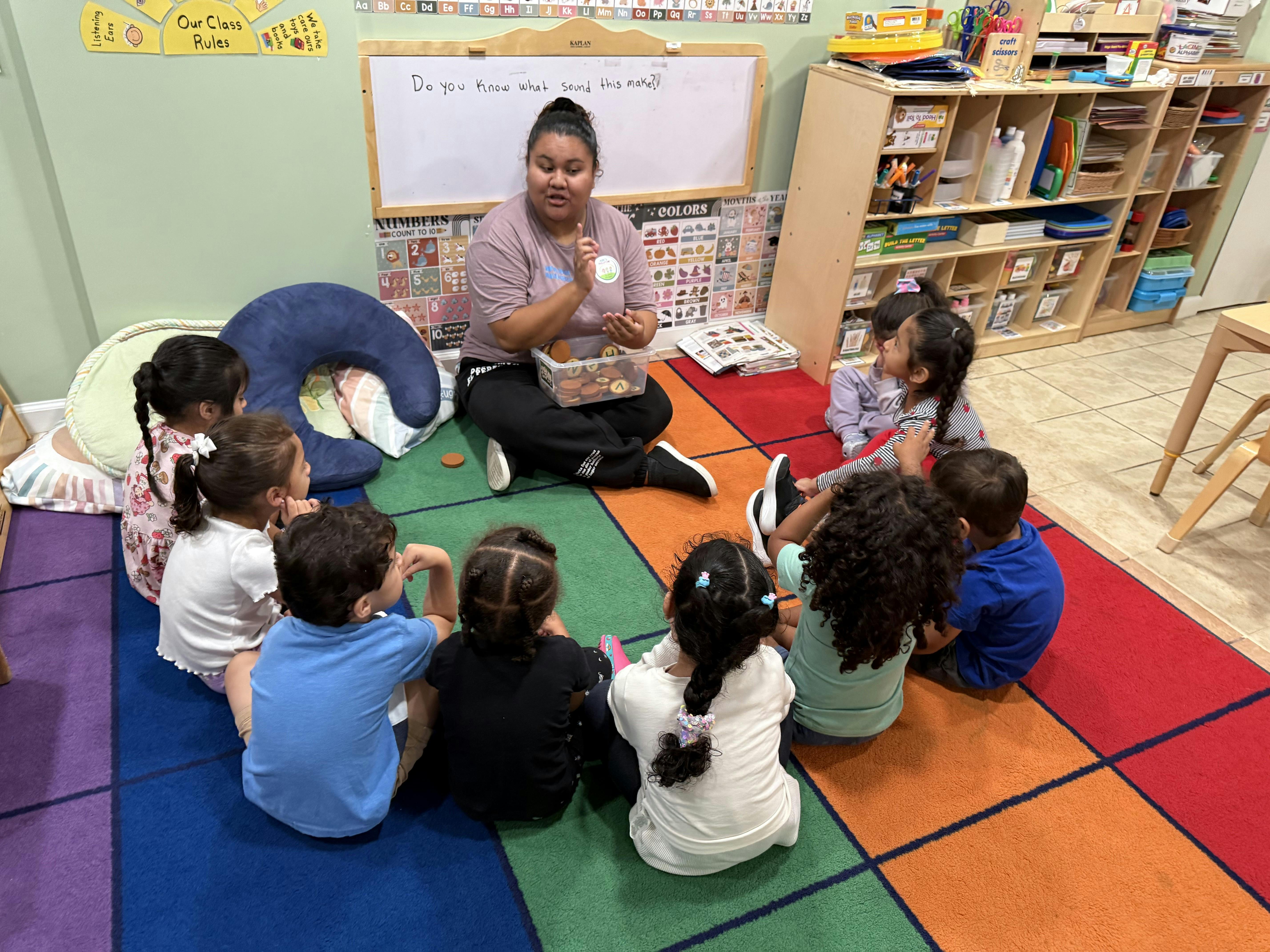 Person sitting on floor with children in a classroom