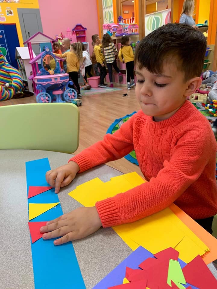 Child arranging colorful paper shapes on a table