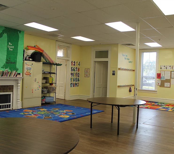 Classroom with tables, colorful rugs, and learning materials