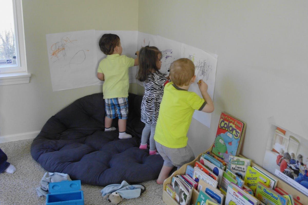 Three children drawing on paper on a wall