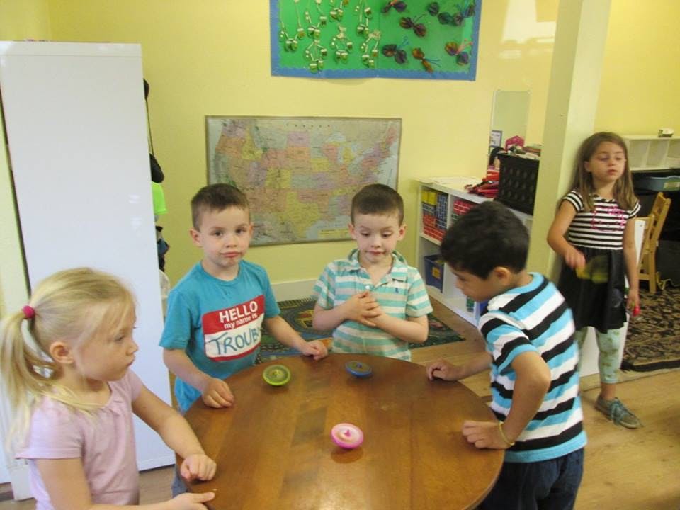 Children playing with spinning tops at a table