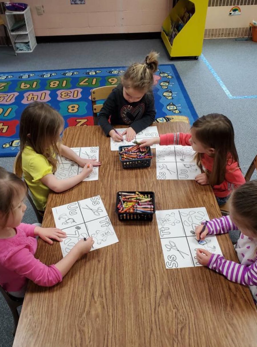 Children coloring at a table in a classroom
