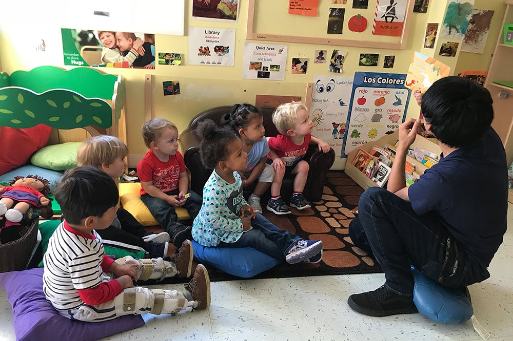 Person reading to a group of children in a classroom