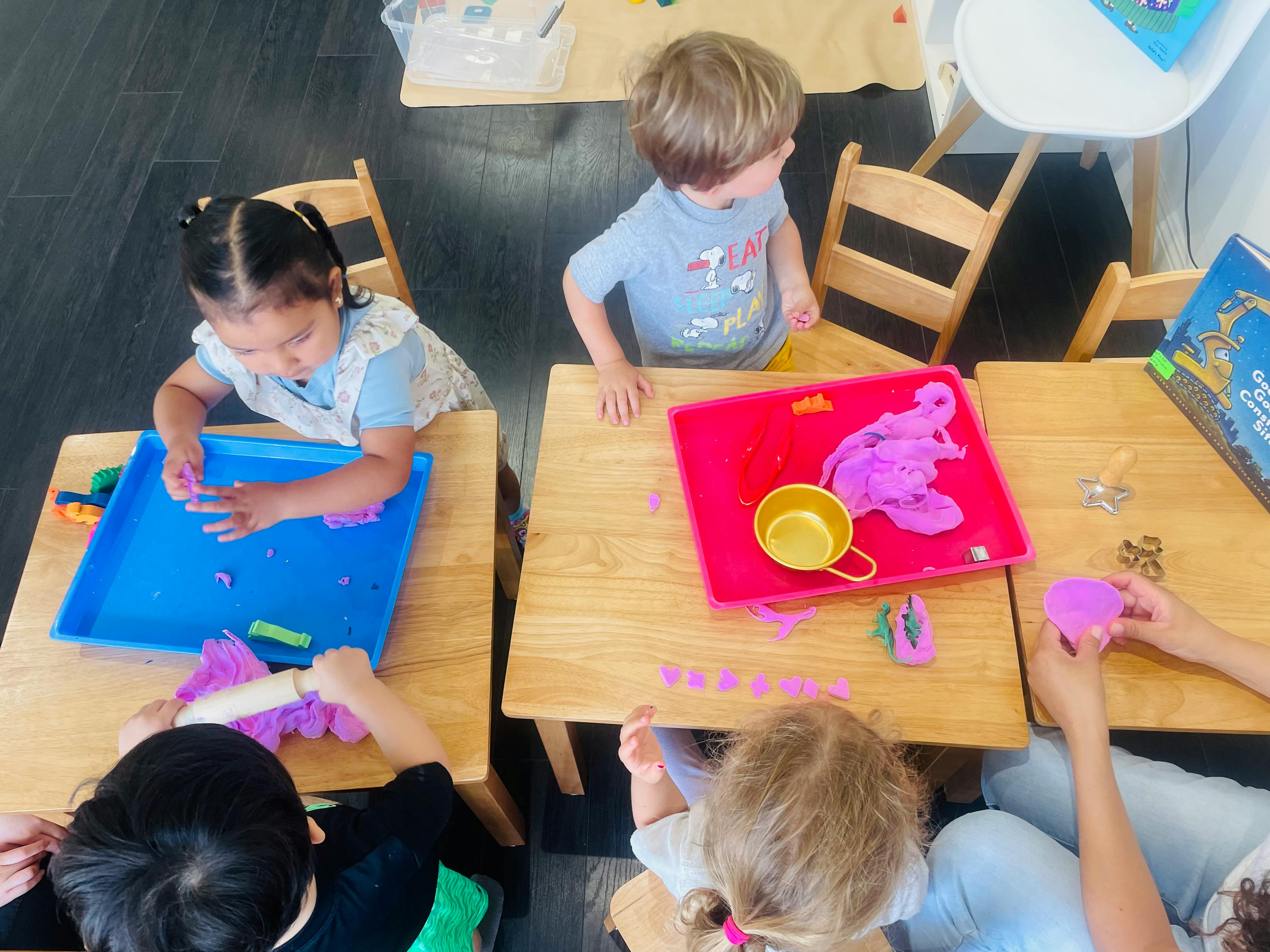 Children playing with colorful dough at small tables