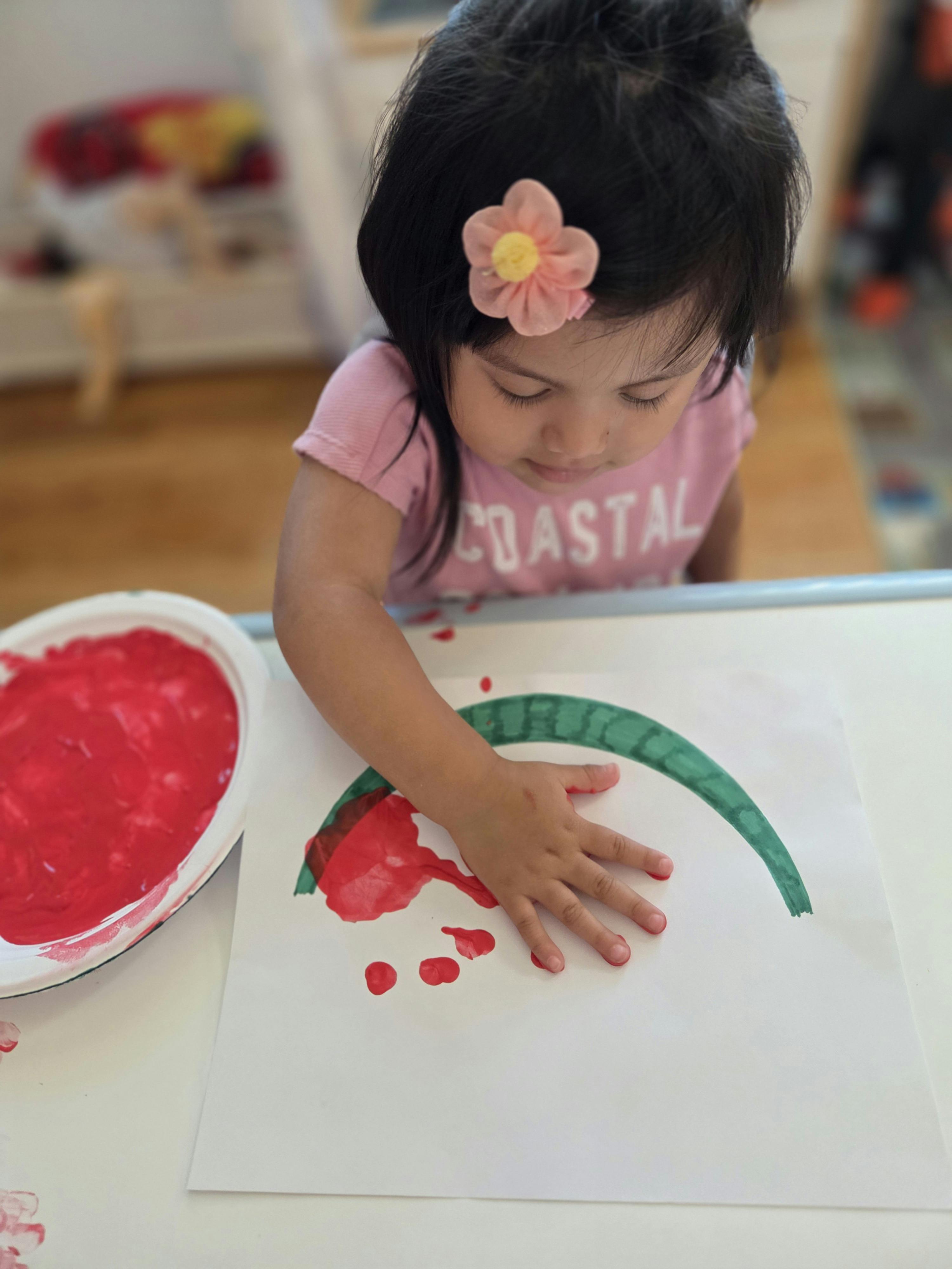 Child finger painting on paper at a table