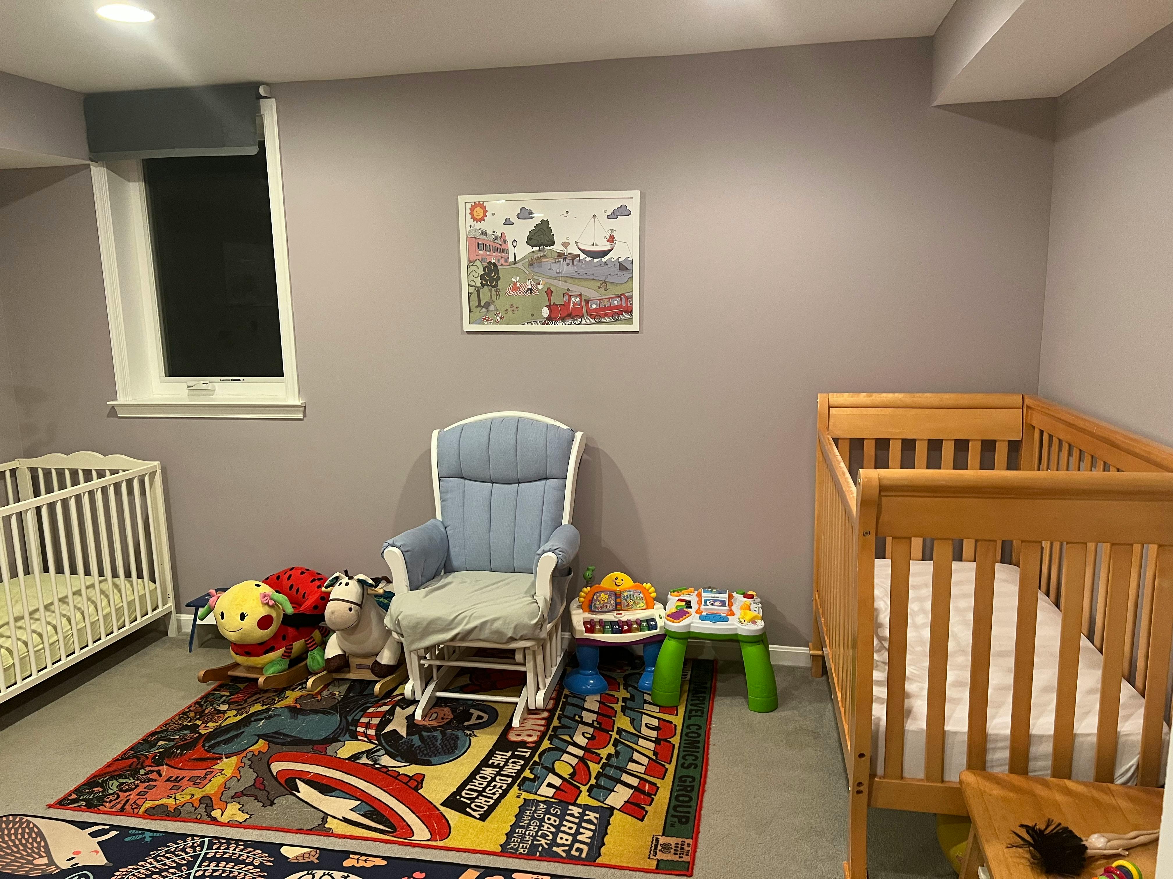 Two cribs, a rocking chair, and toys in a room