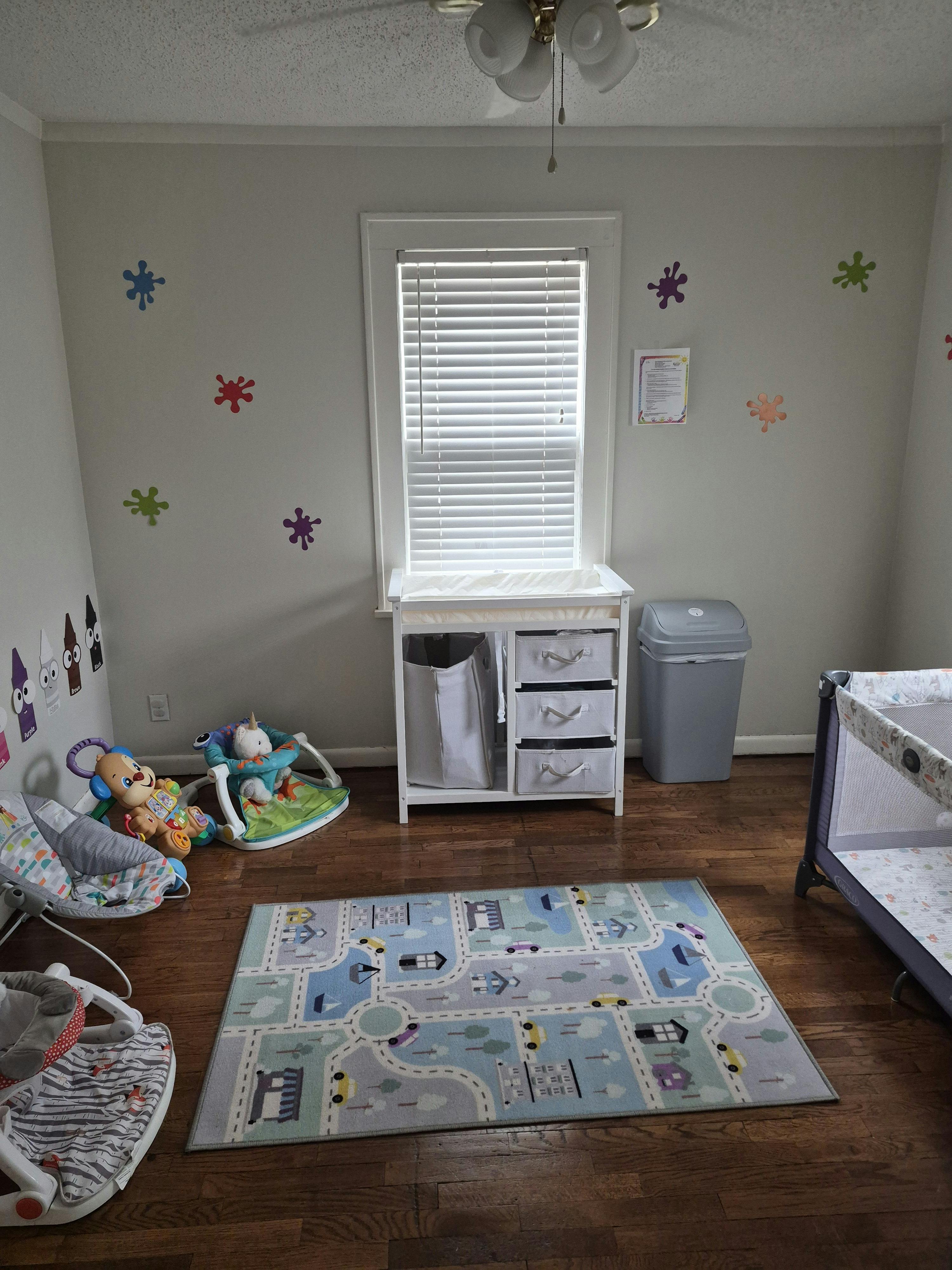 A nursery room with baby furniture, play equipment, and a road-themed rug