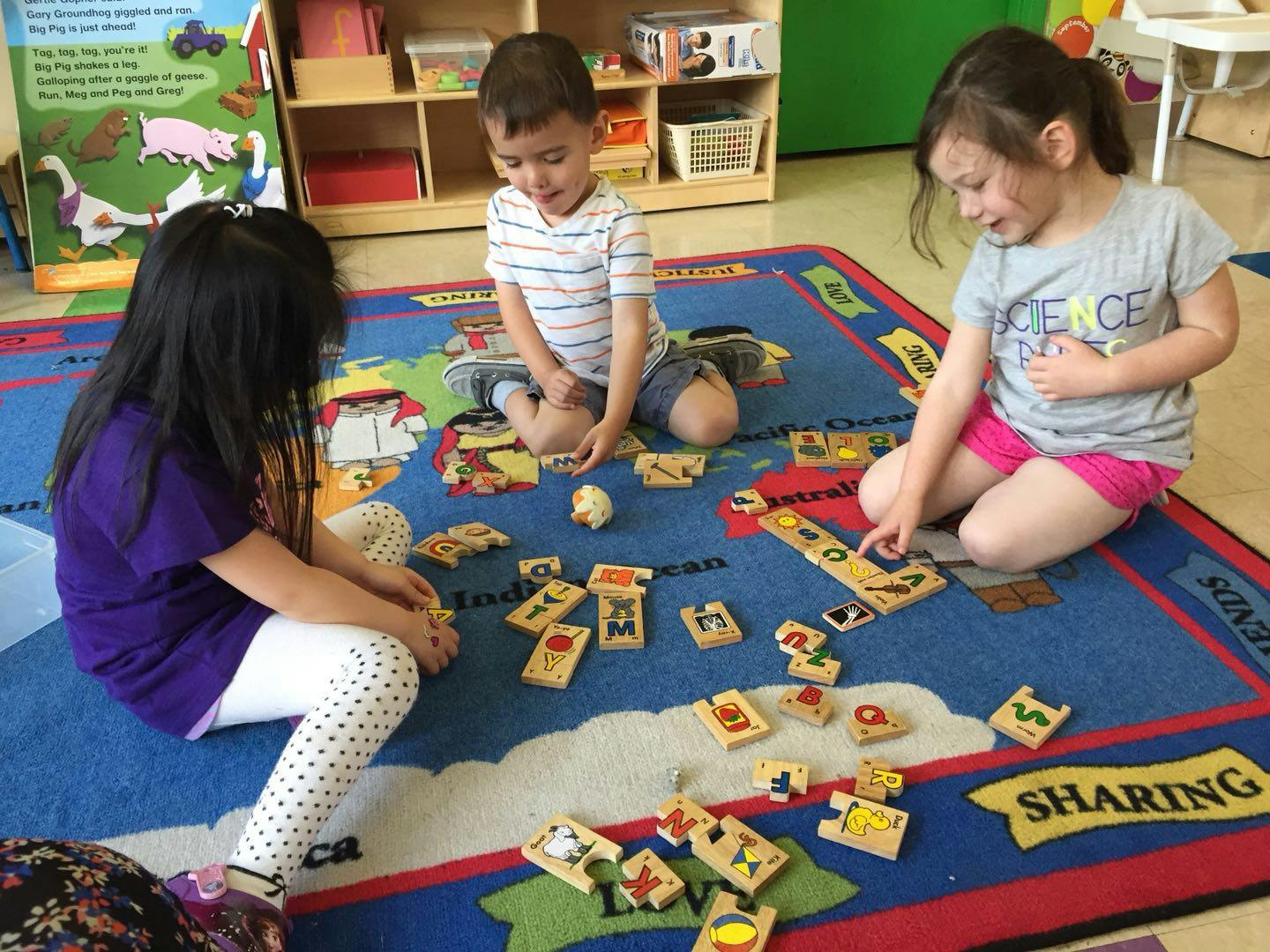 Three children playing with wooden blocks on a blue rug