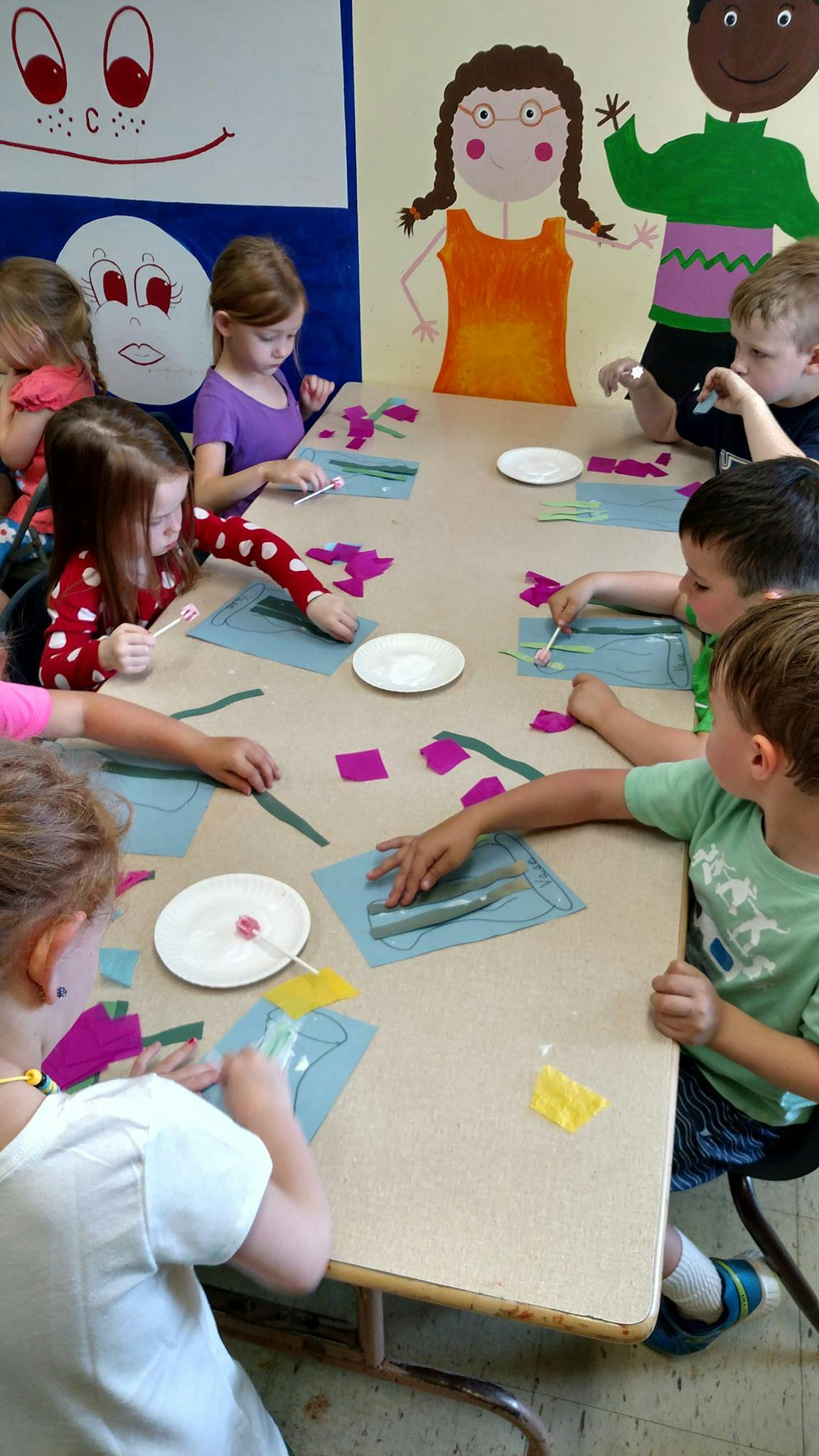 Children at a table doing crafts with paper and craft supplies