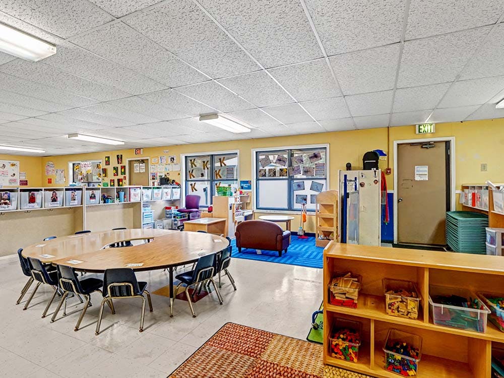 Empty classroom with yellow walls and a large U-shaped table with chairs