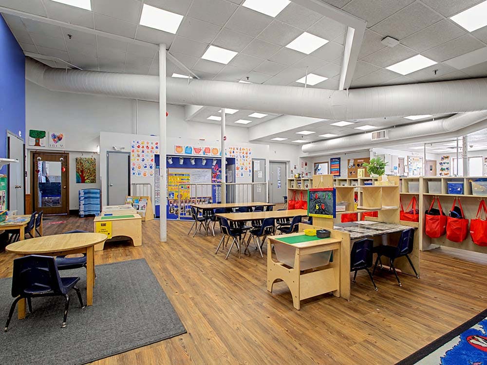 Empty early childhood classroom with small tables and chairs
