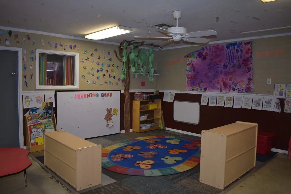 Classroom with a colorful rug, whiteboard, and ceiling fan