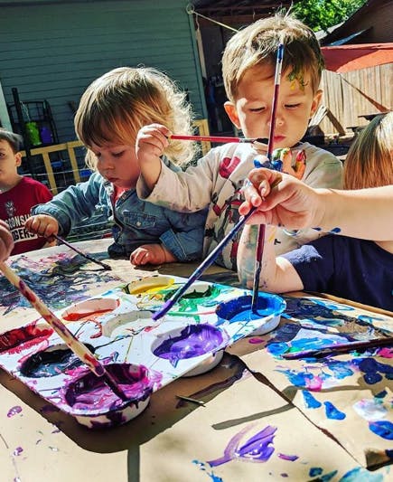 Children painting with brushes and a palette of colors