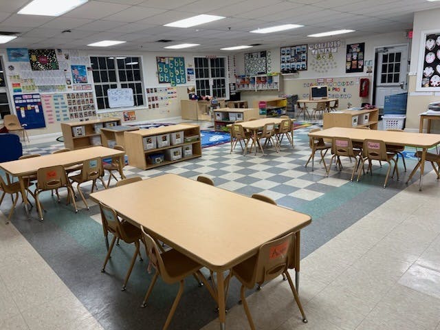 Empty classroom with small desks and chairs, learning materials on walls
